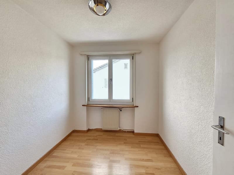 Empty room, white walls, wooden floor, a window, a white radiator, a white ceiling lamp