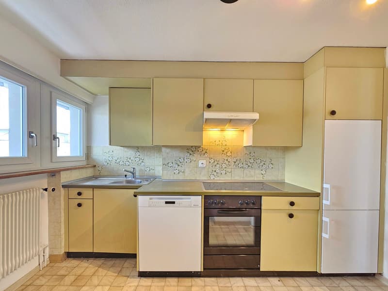 Modern kitchen with yellow cabinets, tiled floor, stainless steel sink, built-in dishwasher, electric stove, and refrigerator.