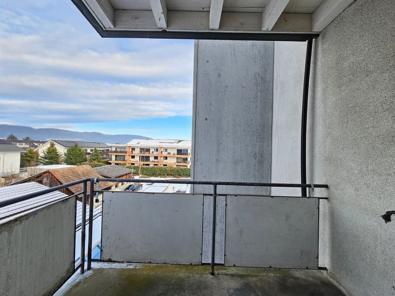 Balcony with railings and concrete floor, view of buildings and mountains