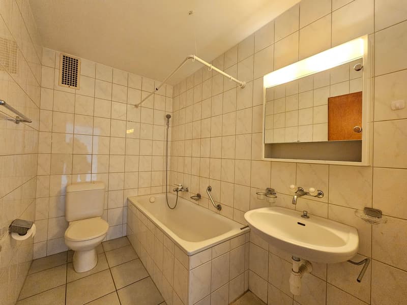 Modern bathroom with bathtub, toilet, sink, mirror, and white tiled walls