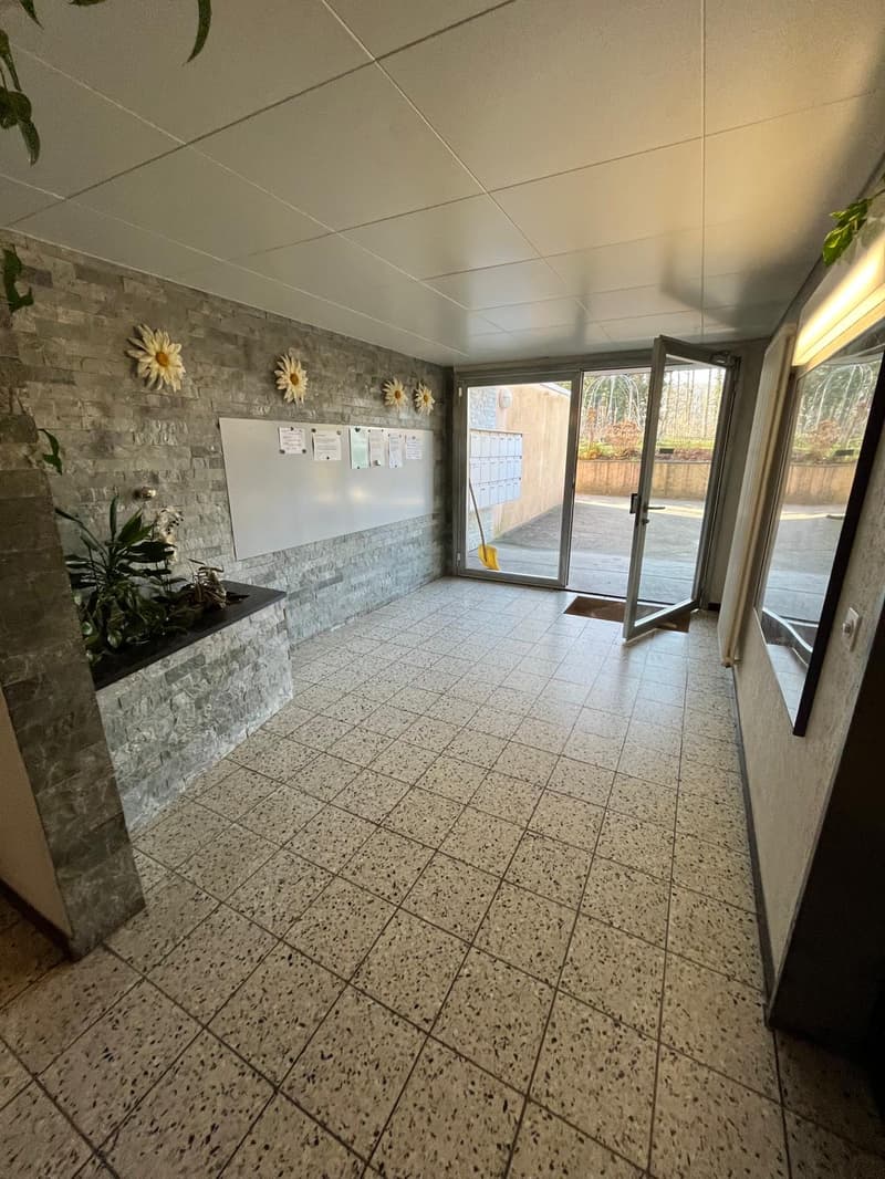 Empty room, tiled floor, sliding doors, potted plant, bulletin board with papers