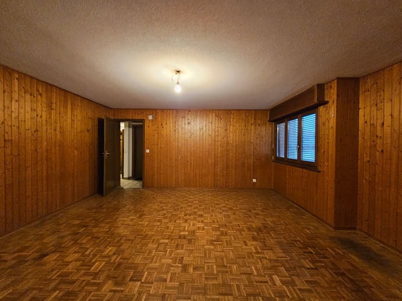 Empty room, wooden walls, parquet floor, one open door, one closed door, window with blinds
