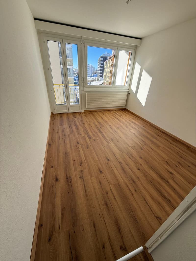 hardwood floors, glass sliding doors, balcony, white walls, view of the city