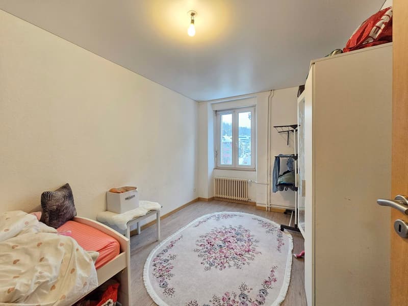 bedroom with single bed, rug, stool, storage box, pillow, radiator