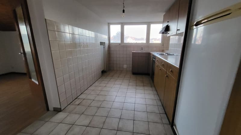 Open kitchen, white tiled walls, wooden cabinets, white refrigerator, small sink, tile flooring