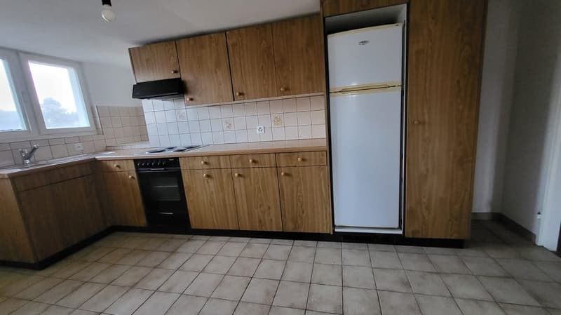 Brown wooden cabinets, white refrigerator, white wall, white tile floor, black oven