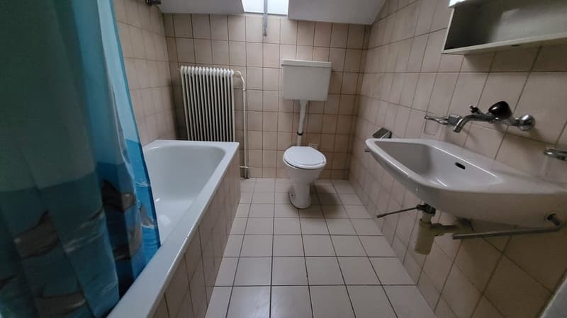 White bathtub, toilet, sink, radiator, tiled walls and floor