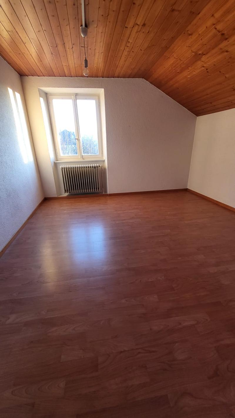 Empty room with wooden flooring, wooden ceiling, radiator under window, window