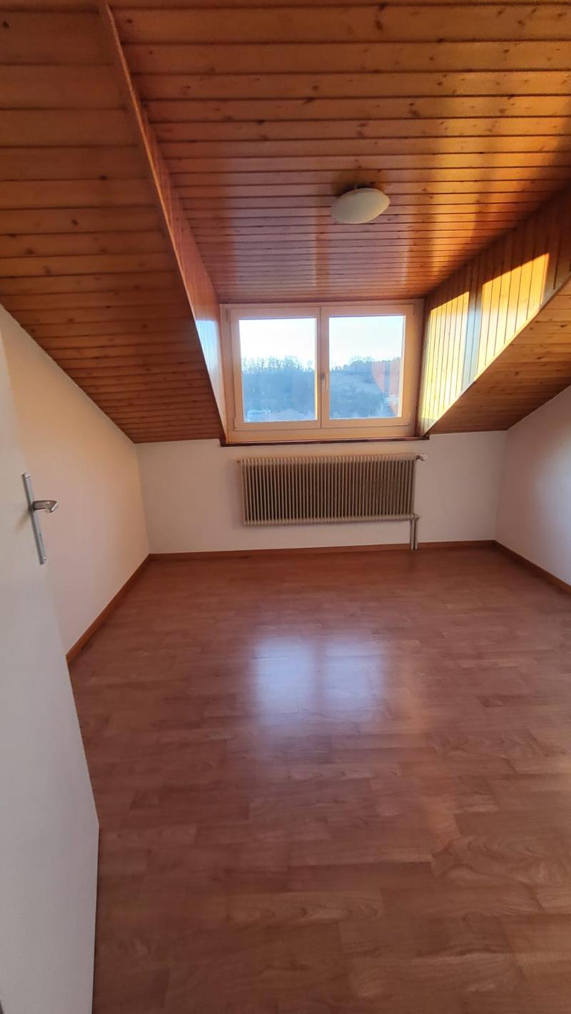 Empty room with hardwood floor, white walls, a ceiling lamp, large window, and a radiator