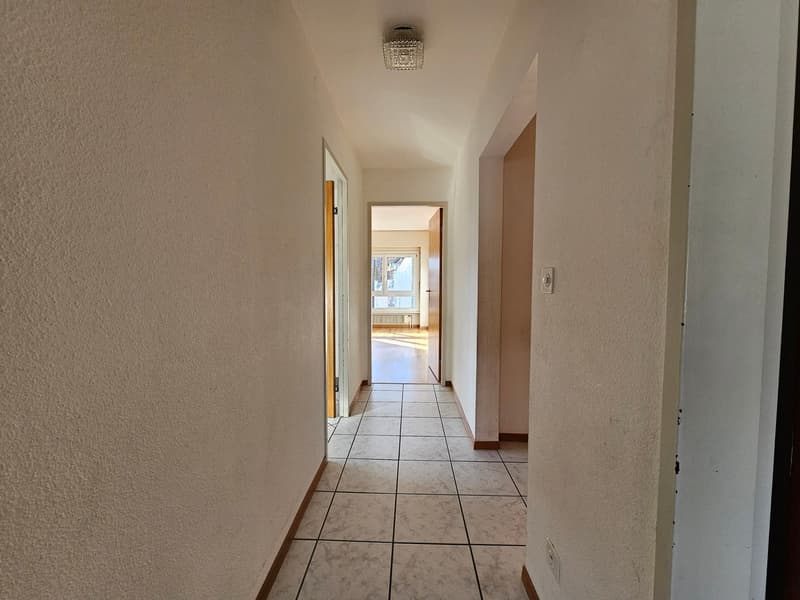 Empty hallway, white walls, tiled floor, two doors, small window