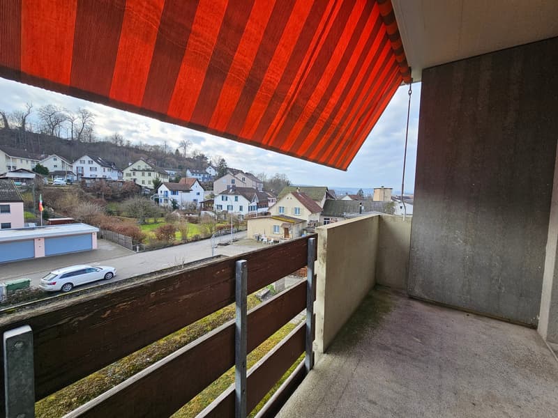 balcony with wooden railings, retractable awning, panoramic view of town