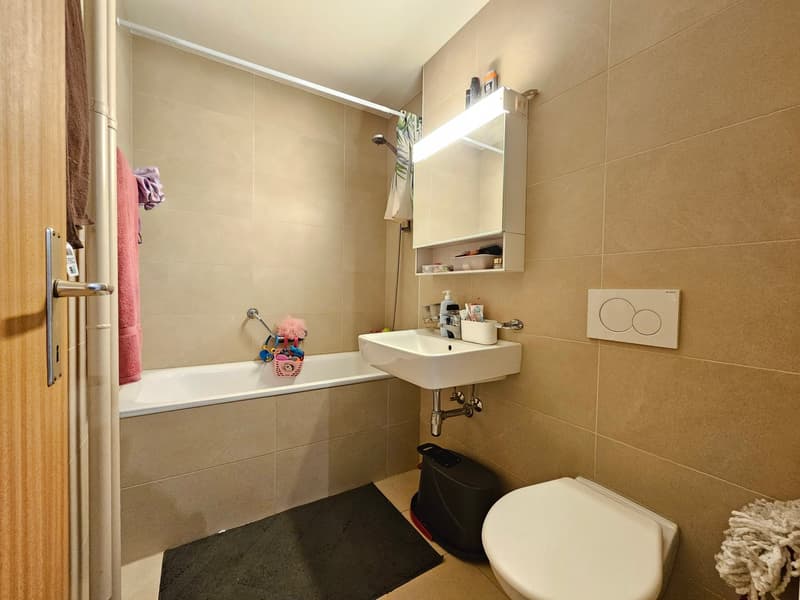 modern bathroom with bathtub, sink, and toilet, wooden door, beige tiles, white shower curtain