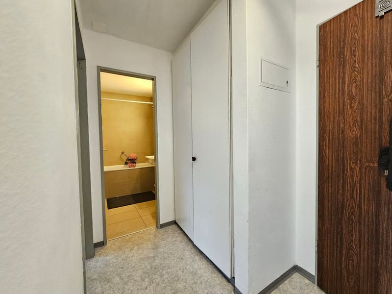 White walls, tiled floor, open door, bathtub, shower area, cabinets, white toilet