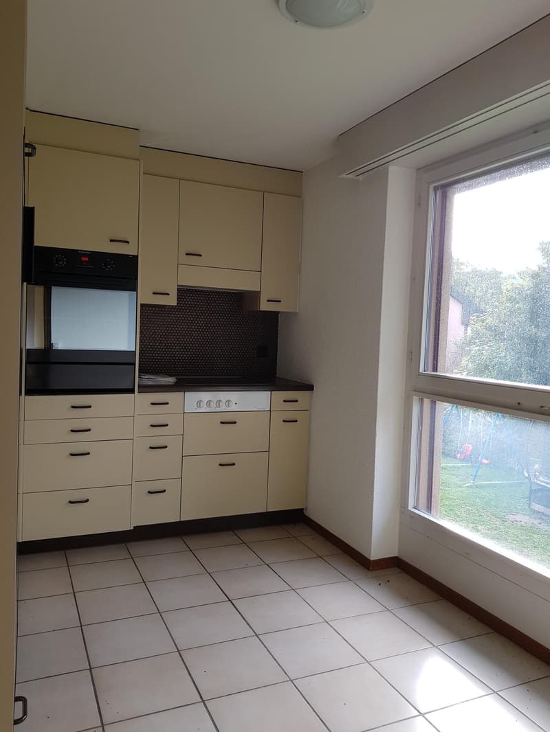 white tiled floor, oak cabinets, built-in oven, dishwasher, window overlooking playground