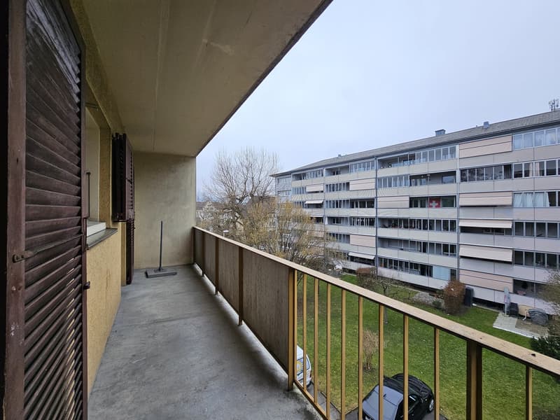 Apartment balcony, metal railing, tiled floor, parked cars