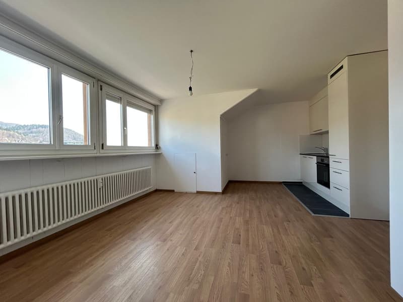 empty room, wooden floor, white walls, large windows, kitchen with oven and sink