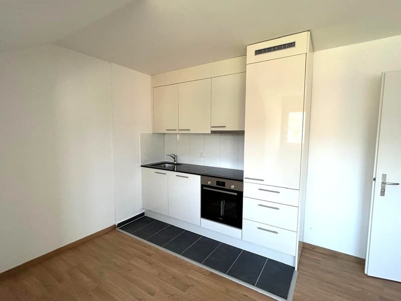 modern kitchen with white cabinets, black countertops, built-in oven, sink, faucet, wooden floor, white walls