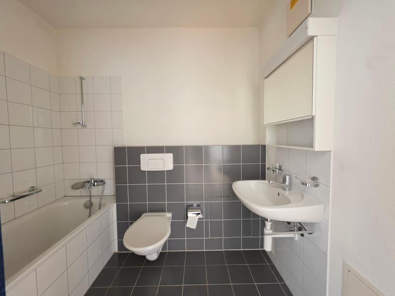 Bathroom with bathtub, toilet, sink, and tiled walls and floor.