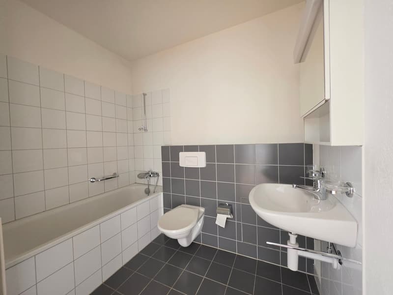 Bathroom with bathtub, toilet, sink, and tiled walls.