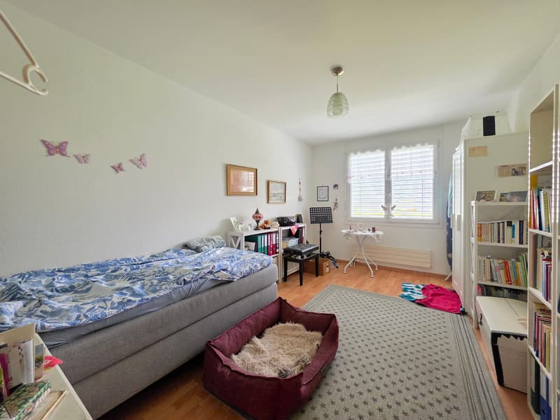 bedroom with bed, dog bed, rug, bookshelf, desk, chair, radiator, window with blinds