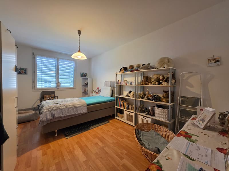 Bedroom with bed, shelves, basket, chair, lamp, rug, and window with blinds