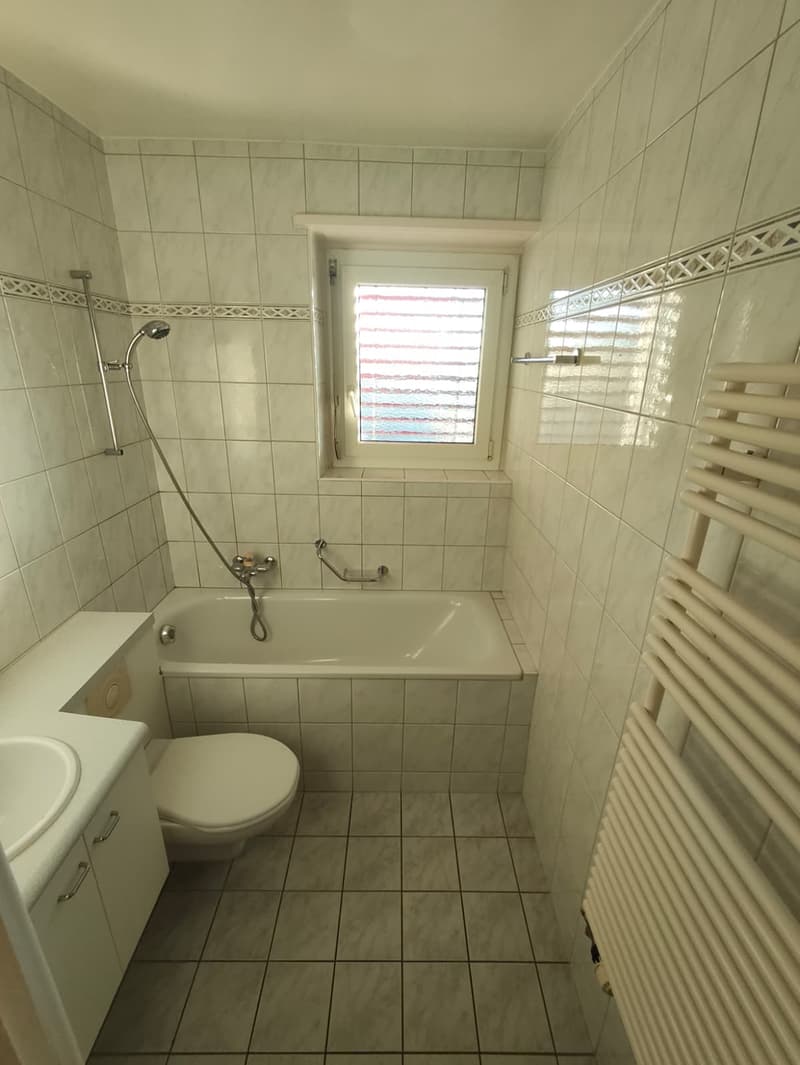 Bathroom with white tiles, bathtub, shower, toilet, sink, and towel rack