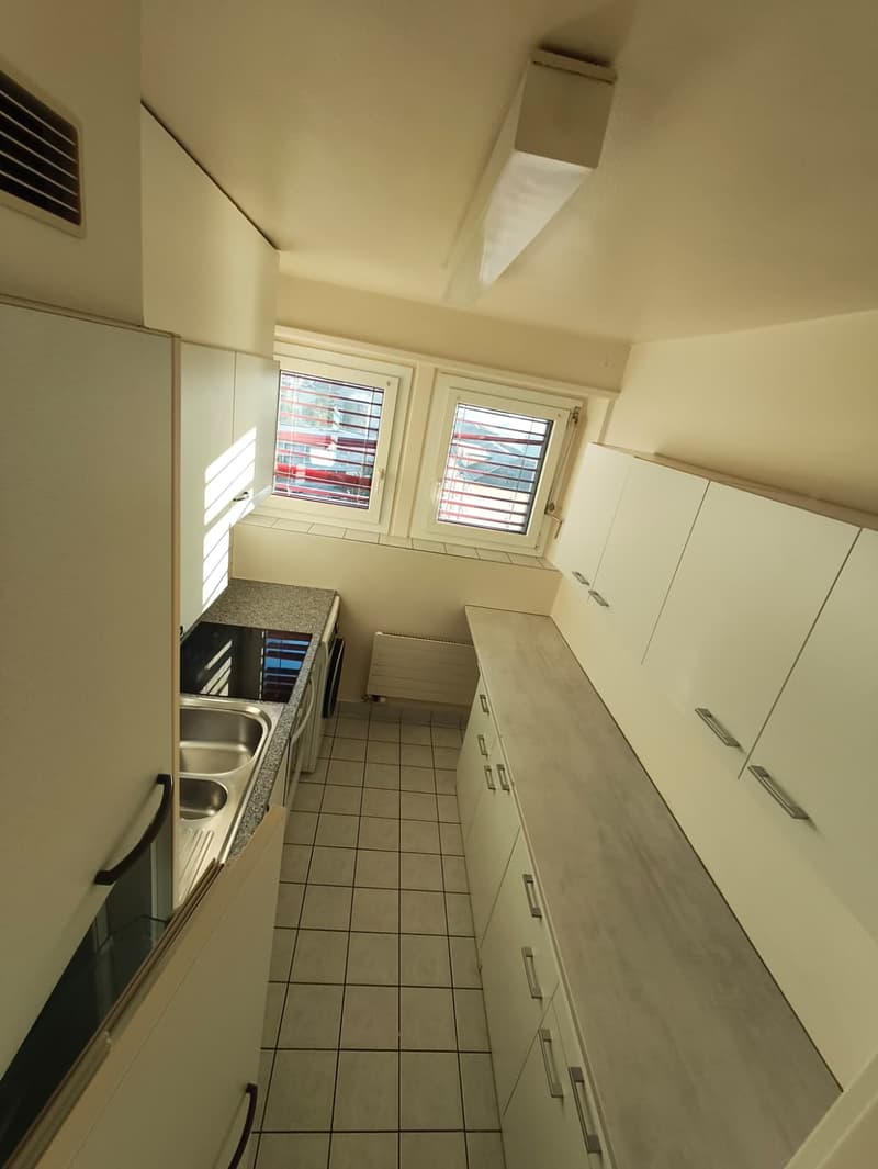 modern kitchen with white cabinets, tiled floor, double sink, gas stove, windows with blinds
