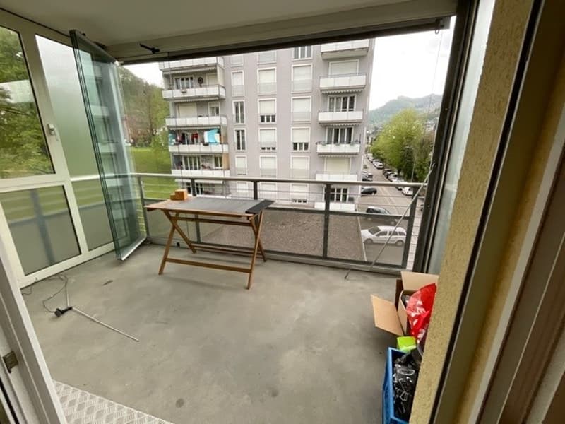 Balcony with table, boxes, and a view of the street and buildings
