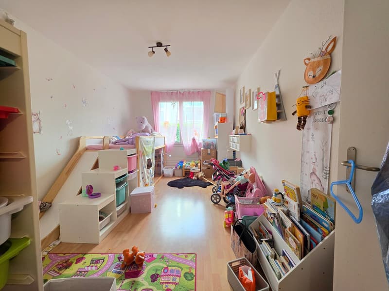 Children's room with bunk beds, toys, shelves, carpet, and a window with curtains