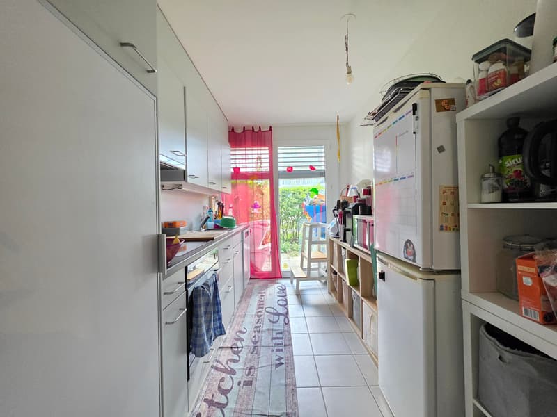 modern kitchen with white cabinets, tiled floor, open door to garden, appliances, shelves with storage items