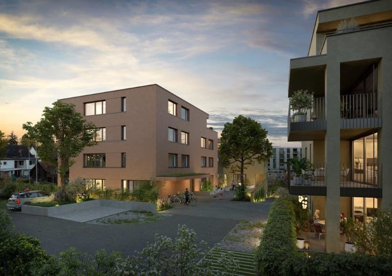 3-story apartment building with balconies, surrounded by trees and landscaping, with a paved courtyard area for parking and pedestrian access