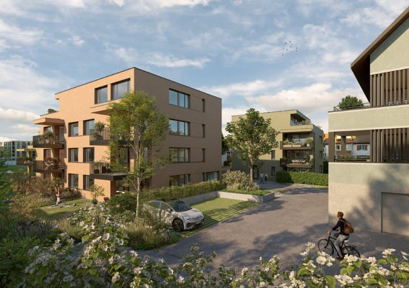 Multi-story apartment building with balconies, surrounded by landscaped gardens and walkways, with a person riding a bicycle in the foreground