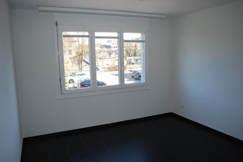 Empty room with white walls, large window with exterior view