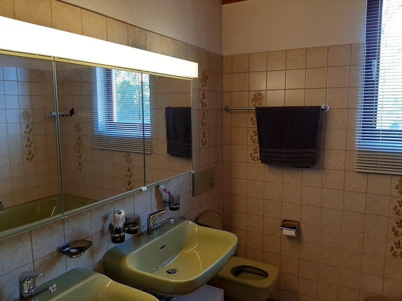 Bathroom with two sinks, mirror, toilet, and towel rack