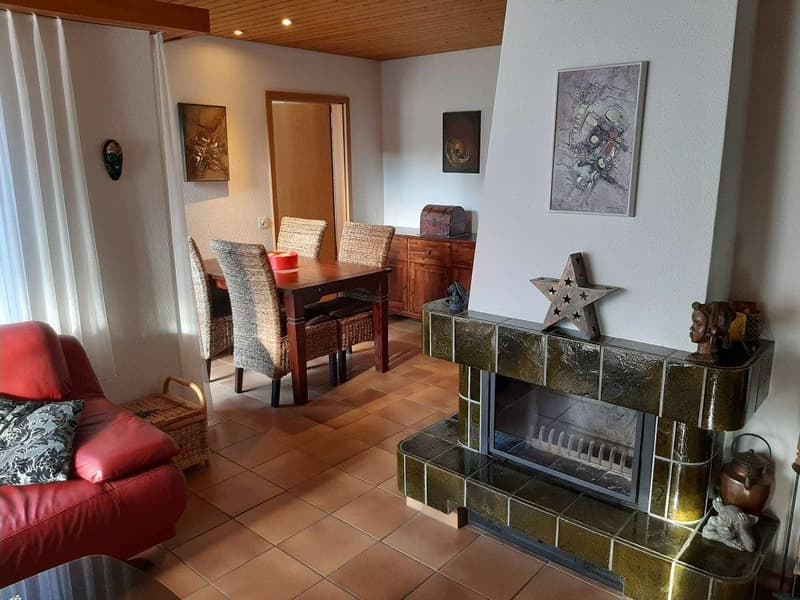 living room with fireplace, dining table, chairs, wooden cabinet, paintings, red couch, decorative items