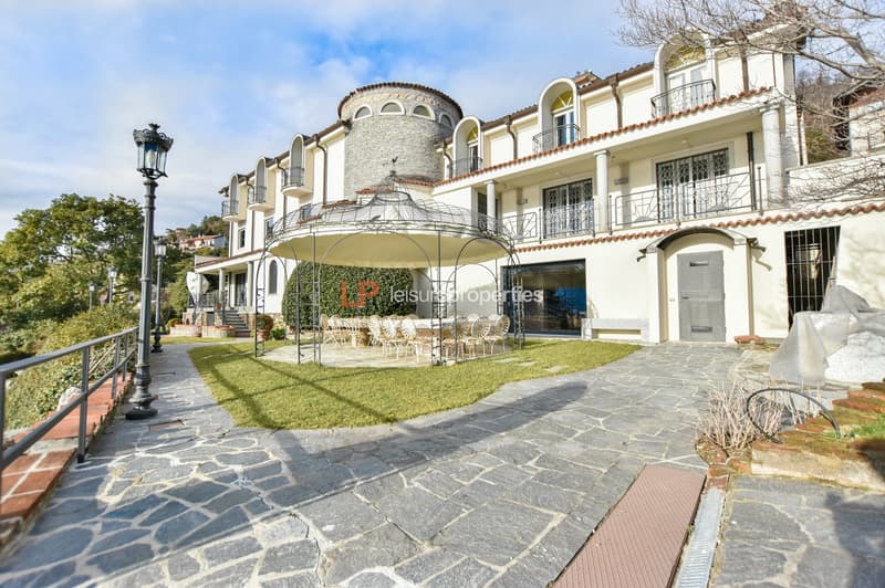 White villa, large gazebo, garden with grass, pathways, multiple windows, balconies, outdoor dining area