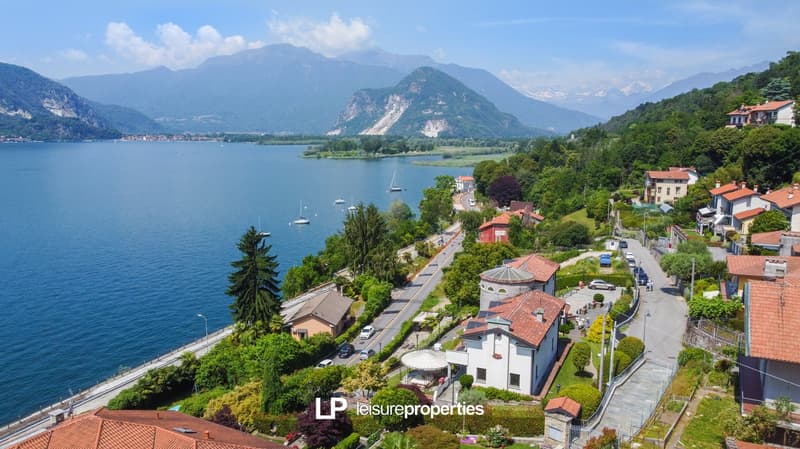 House overlooking a lake with mountains in the background, several houses and a road