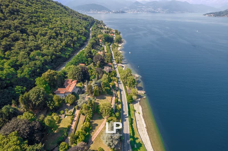 Coastline property, villa, road, lush greenery, shoreline, mountains in the background, water body, aerial perspective, houses