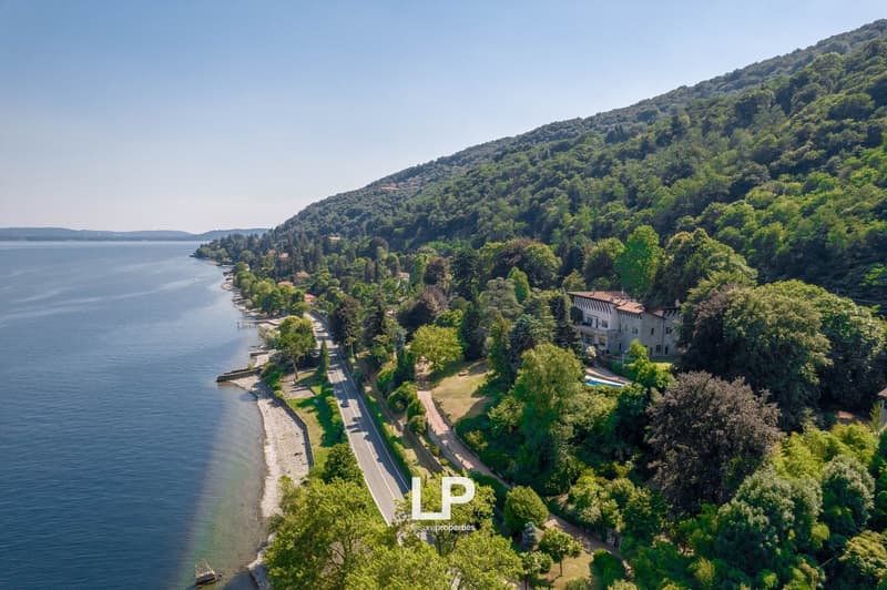 House on hillside with lake view, surrounded by trees, road nearby