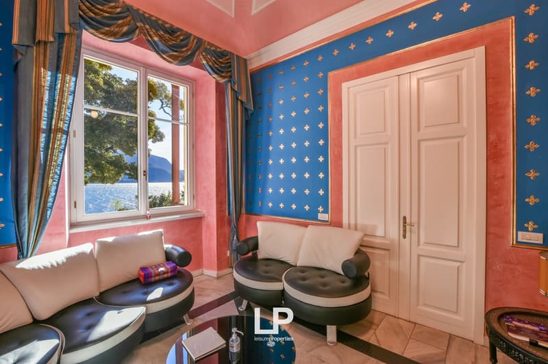 contemporary design with pink and blue walls, large windows, couch, armchairs, glass coffee table, lake view
