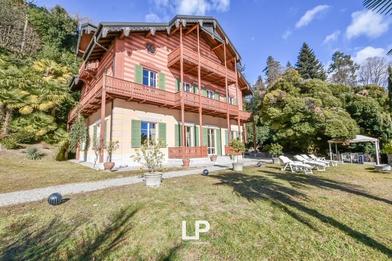 Detached house, red painted wood, green window shutters, balcony, surrounded by trees