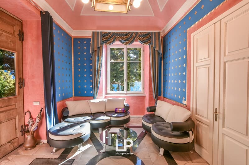 pink and blue walls, large windows, curved sofas, round coffee table, umbrella stand, tiled floor
