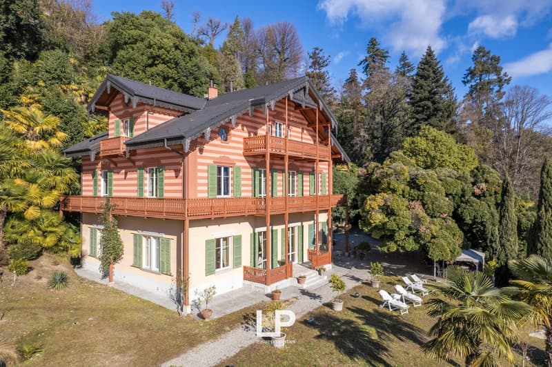 Detached house, multi-storey, multiple balconies, red and beige paint, garden, several palm trees