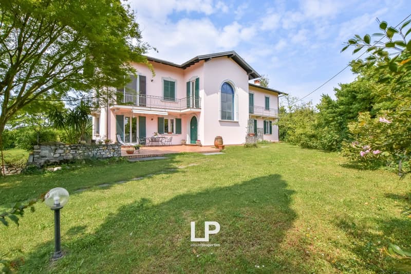 pink house, green shutters, 2 floors, balcony on first floor, garden with patio, outdoor seating area, lawn, trees, good view