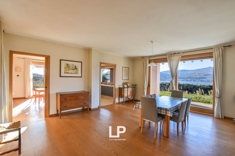 Large room with dining area, wooden floor, large windows, and lake view.