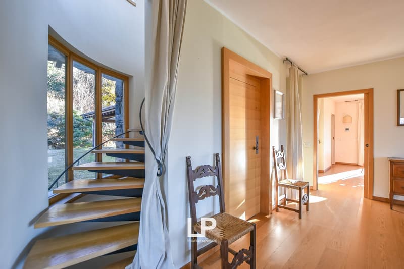 Spacious living area with large windows, wooden staircase, wooden furniture, and a view of the outdoor area.