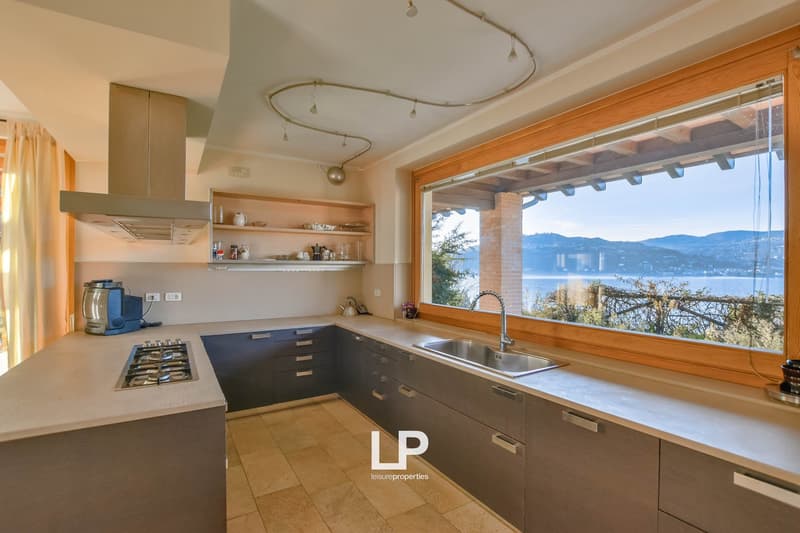 Spacious kitchen with modern appliances, wooden cabinets, and a large window overlooking the lake and mountains.