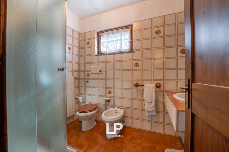 white tiles, brown tiles, toilet, bidet, sink, window, towel rack, radiator