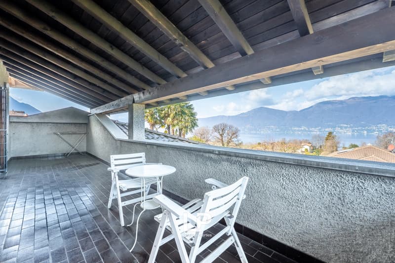 Balcony with table and chairs, tiled floor, view of mountains and water