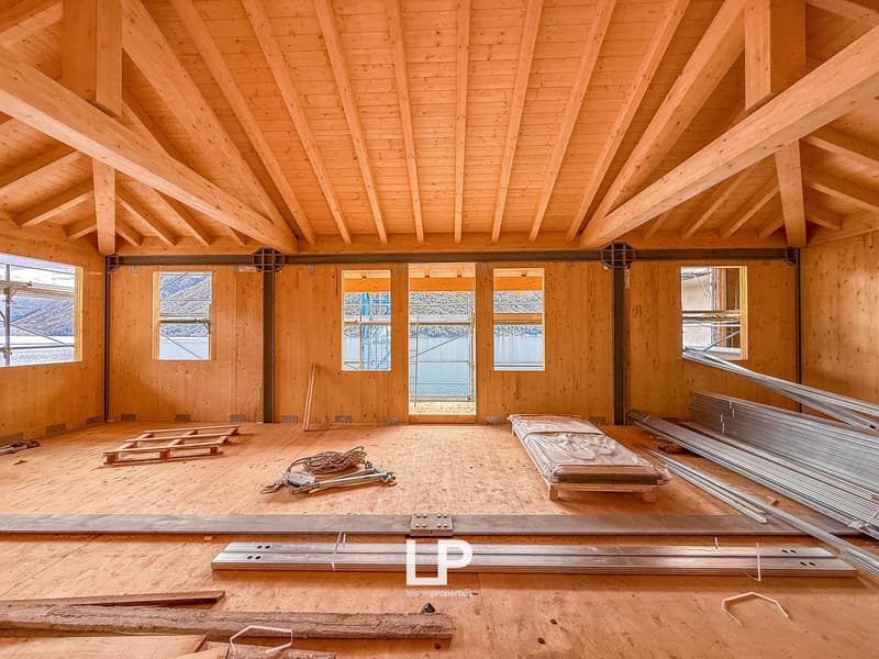 large open room, wooden walls, large windows, unfinished floor, exposed wooden beams